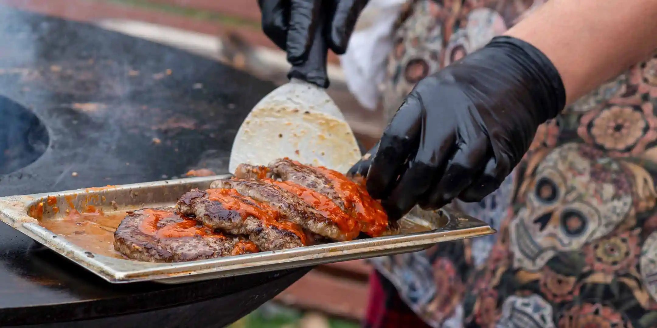 Ein Mann legt mariniertes Fleisch zum Grillen auf eine Servierplatte Genussio